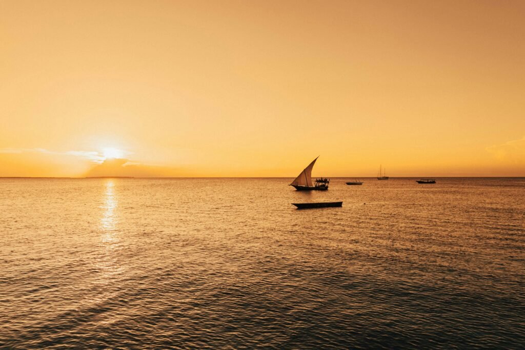 Serene sailboat scene with a golden sunset over the Indian Ocean in Zanzibar, Tanzania.